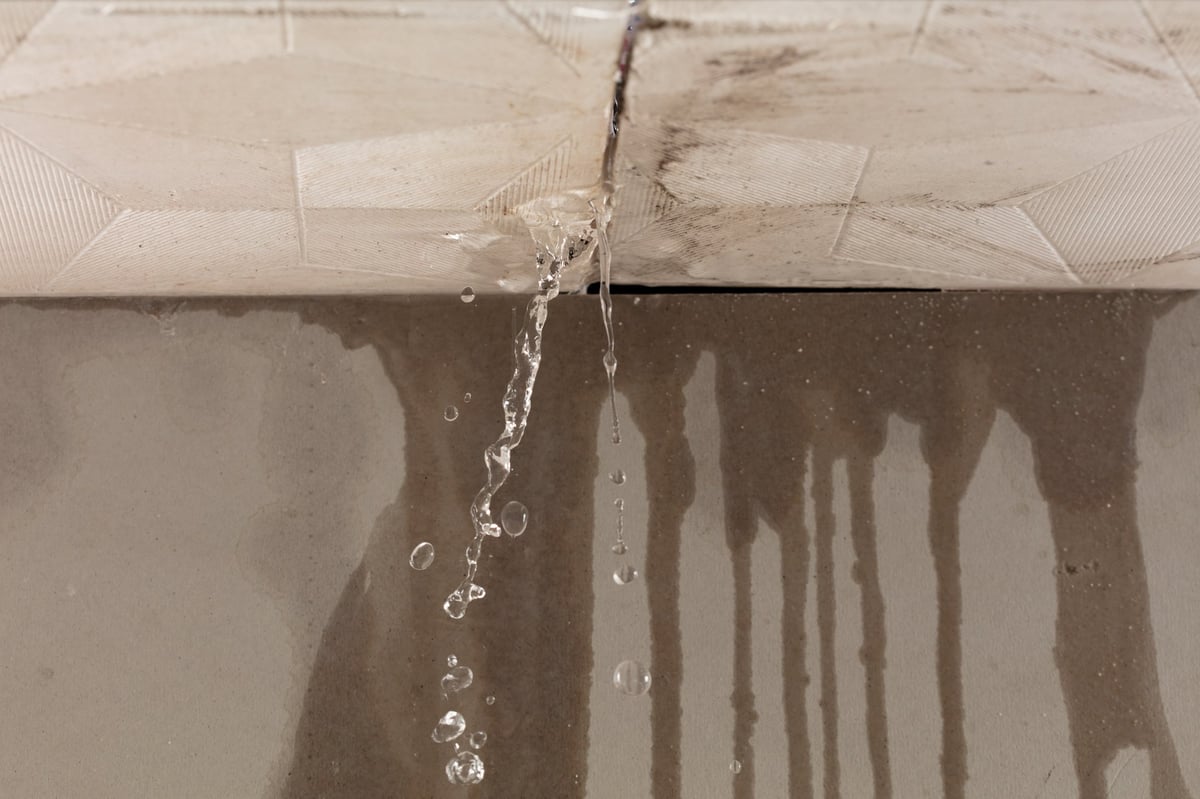 Heavy storm rain create water flow from edge of ceiling and dirty stain on wall. Water leaking from top ceiling as droplets and flow in old house